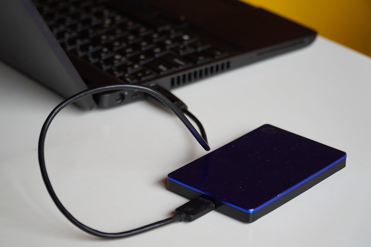 Disque dur externe posé à côté d'un ordinateur portable sur un bureau en bois